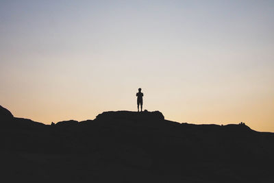 Silhouette man standing on shore against sky during sunset
