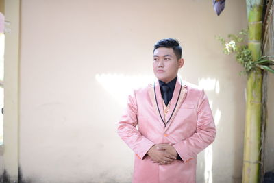 Portrait of young man standing against wall