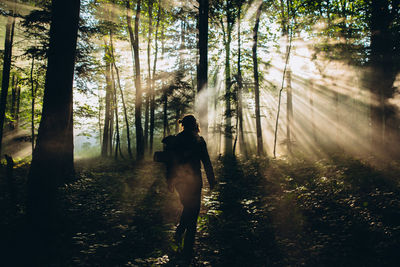 Man with backpack walking in forest against trees