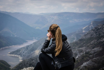 Rear view of woman standing on mountain against sky