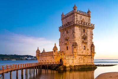 View of historic building by sea against sky in city