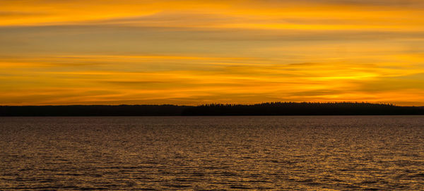 Scenic view of sea against dramatic sky during sunset