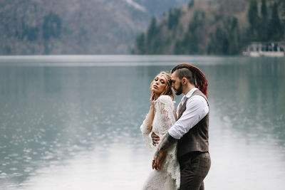 A happy couple in love and married embrace in nature by the lake and the misty mountains