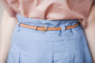 Midsection of woman wearing belt on blue skirt