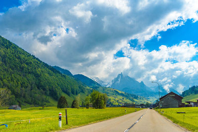 Scenic view of road by mountains against sky