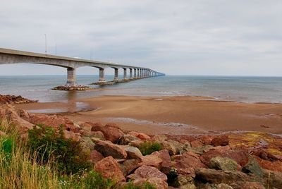 Bridge over sea shore against sky