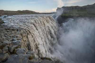 Scenic view of waterfall against sky