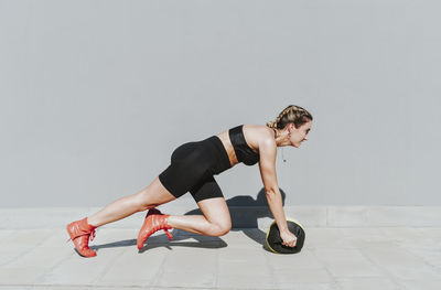 Young athlete with medicine ball exercising on sunny day