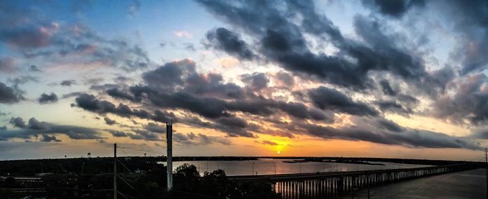 Scenic view of sea against cloudy sky during sunset