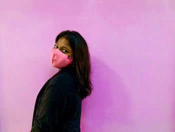 Portrait of young woman standing against wall