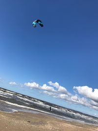 Low angle view of paragliding over beach against sky