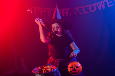 Midsection of woman holding pumpkin against red background