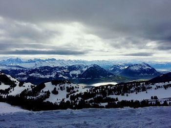 Scenic view of snowcapped mountains against cloudy sky