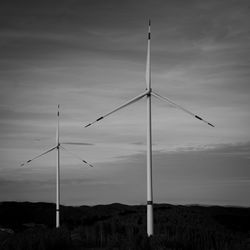 Wind turbines on field against sky