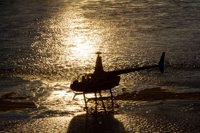 Silhouette boat sailing on sea against sky during sunset