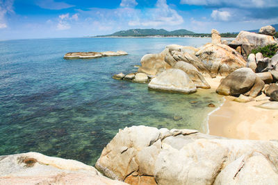 Rocks by sea against blue sky