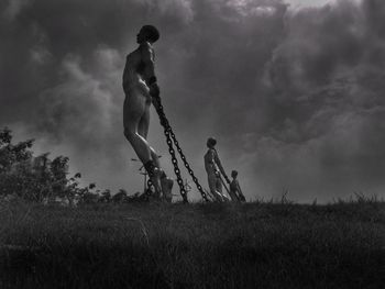 Men standing on field against sky
