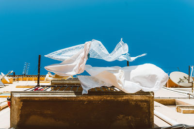 Evocative image of white clean bed sheets flowing and dancing in the wind in day against blue sky