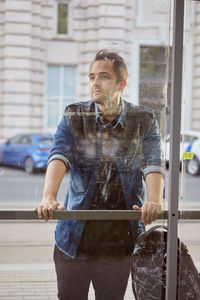 Man standing against glass window