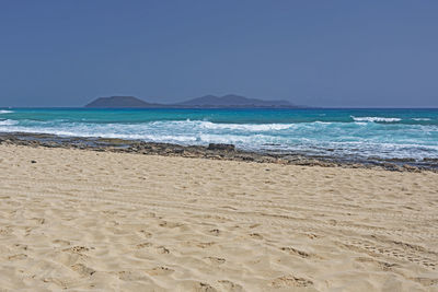 Scenic view of beach against clear blue sky