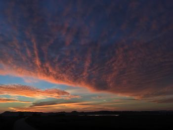 Silhouette landscape against dramatic sky during sunset