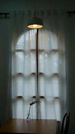 Close-up of lamp against window at home