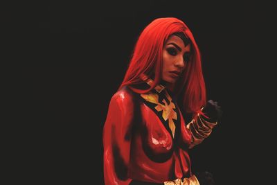 Young woman with red body paint against black background