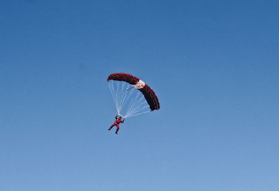 Low angle view of person paragliding against clear blue sky