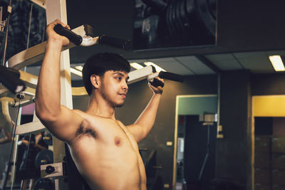 Shirtless young man exercising in gym
