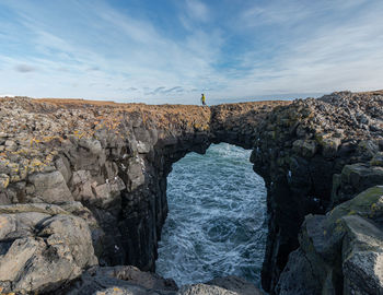 Full frame view of a tourist walking over a natural land-bridge above the churning ocean waters