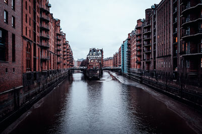 Canal amidst buildings in city against sky