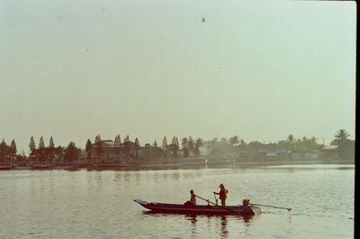 People in boat on river against sky
