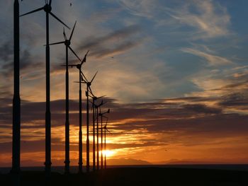 Low angle view of silhouette electricity pylon against sky during sunset