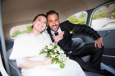 Portrait of happy newly wed couple sitting in car