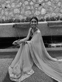 Smiling woman wearing sari while sitting on footpath