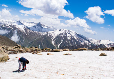 Rear view of boy walking on snowcapped mountains