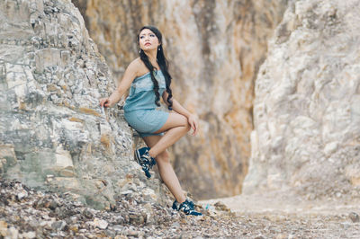 Side view of young woman leaning on rock formation