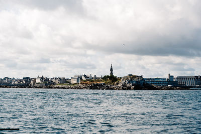 Sea by buildings against sky in city