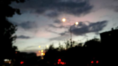 Defocused image of silhouette trees against sky at night