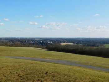 Scenic view of green landscape and sea against sky