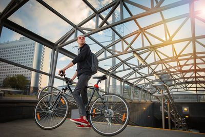 Man looking at bicycle against sky