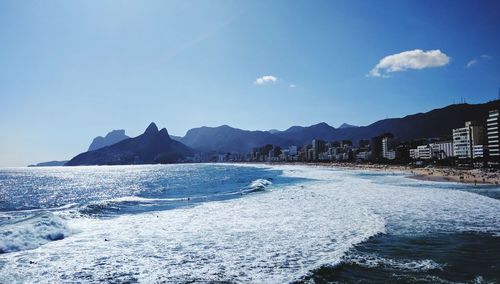 Panoramic view of sea and mountains against blue sky