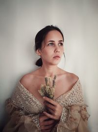 Portrait of young woman standing against wall