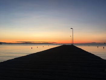 Pier over sea against sky during sunset