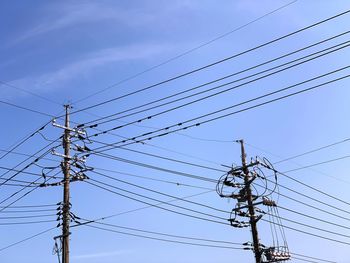 Low angle view of power lines against blue sky