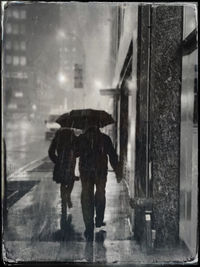 Rear view of people walking on wet street during rainy season