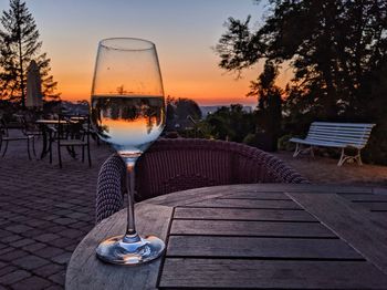 Wine glass on table against sky during sunset