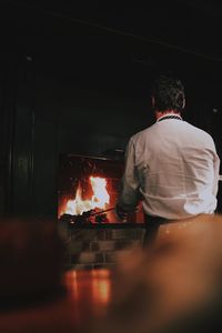 Rear view of chef burning wood in stove