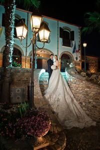 People on illuminated street light by flowering plants