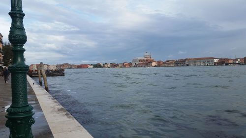 View of old town by river against cloudy sky